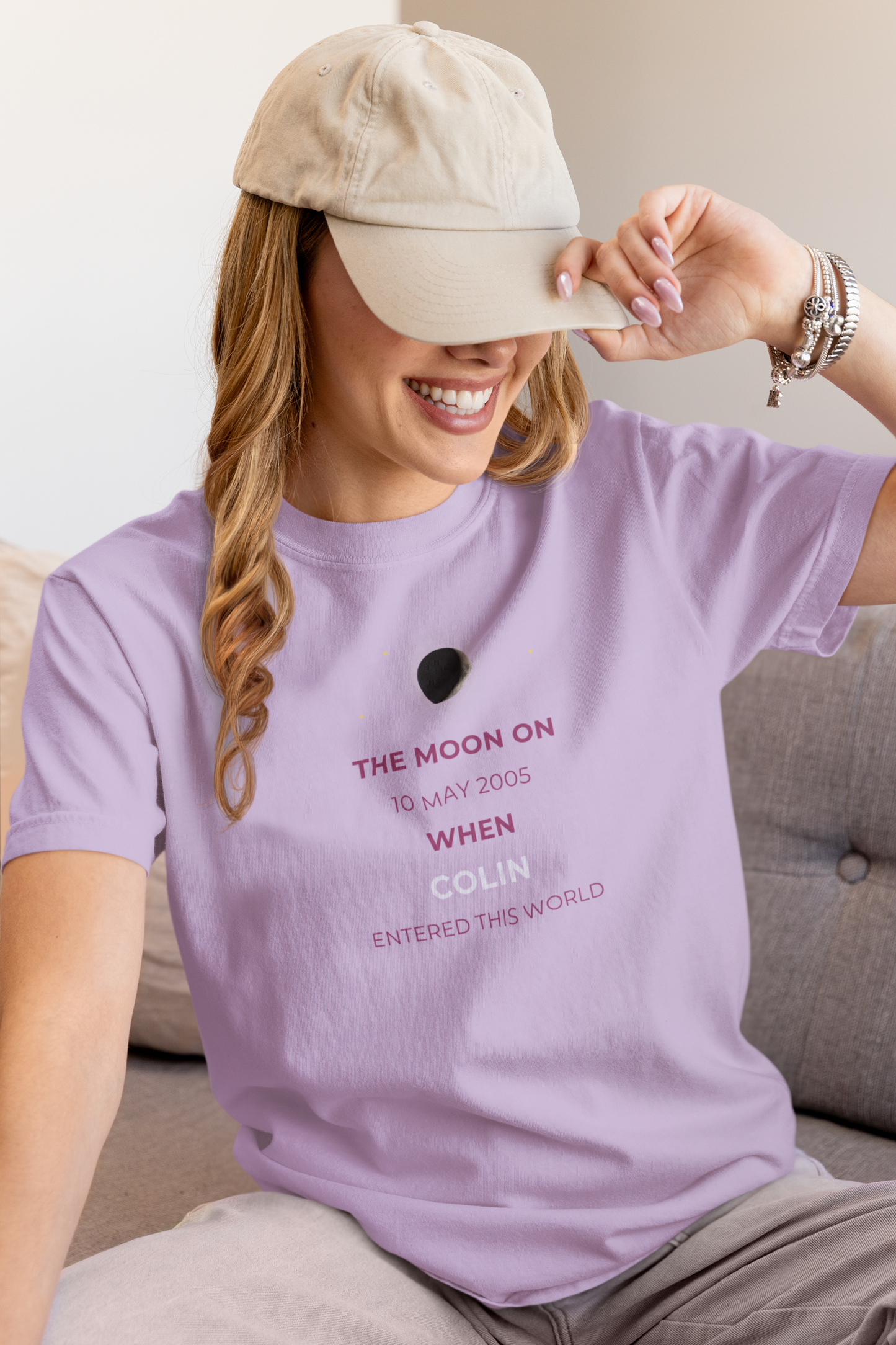 Woman wearing a purple t-shirt with text, sitting on a couch.