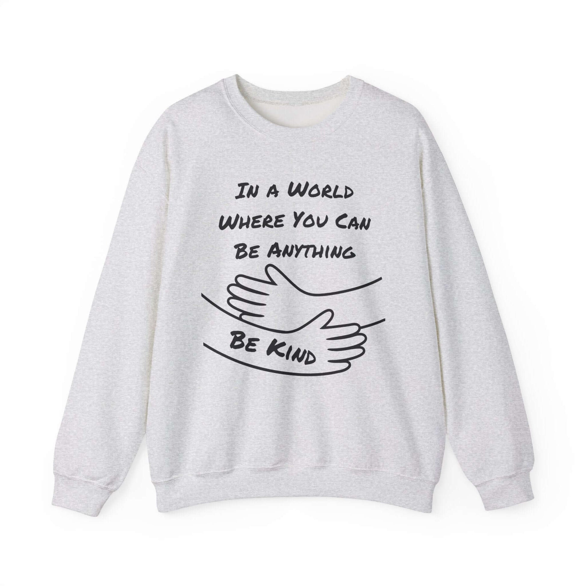 Ash grey sweatshirt with a motivational quote in dark font: “In a world where you can be anything, be kind,” paired with hugging arms artwork. Soft and versatile, ideal for good humans and gifting with meaning.