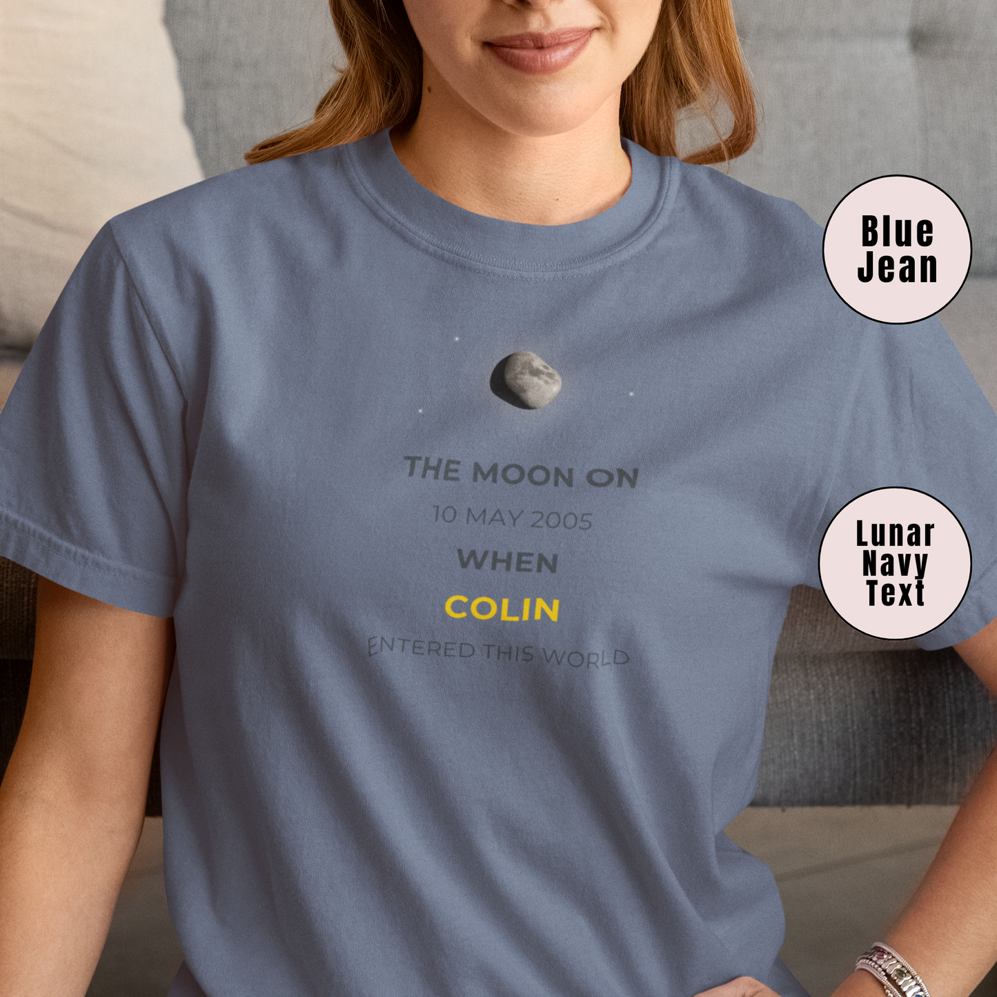 Person wearing a blue t-shirt with text and a moon graphic, sitting on a couch.