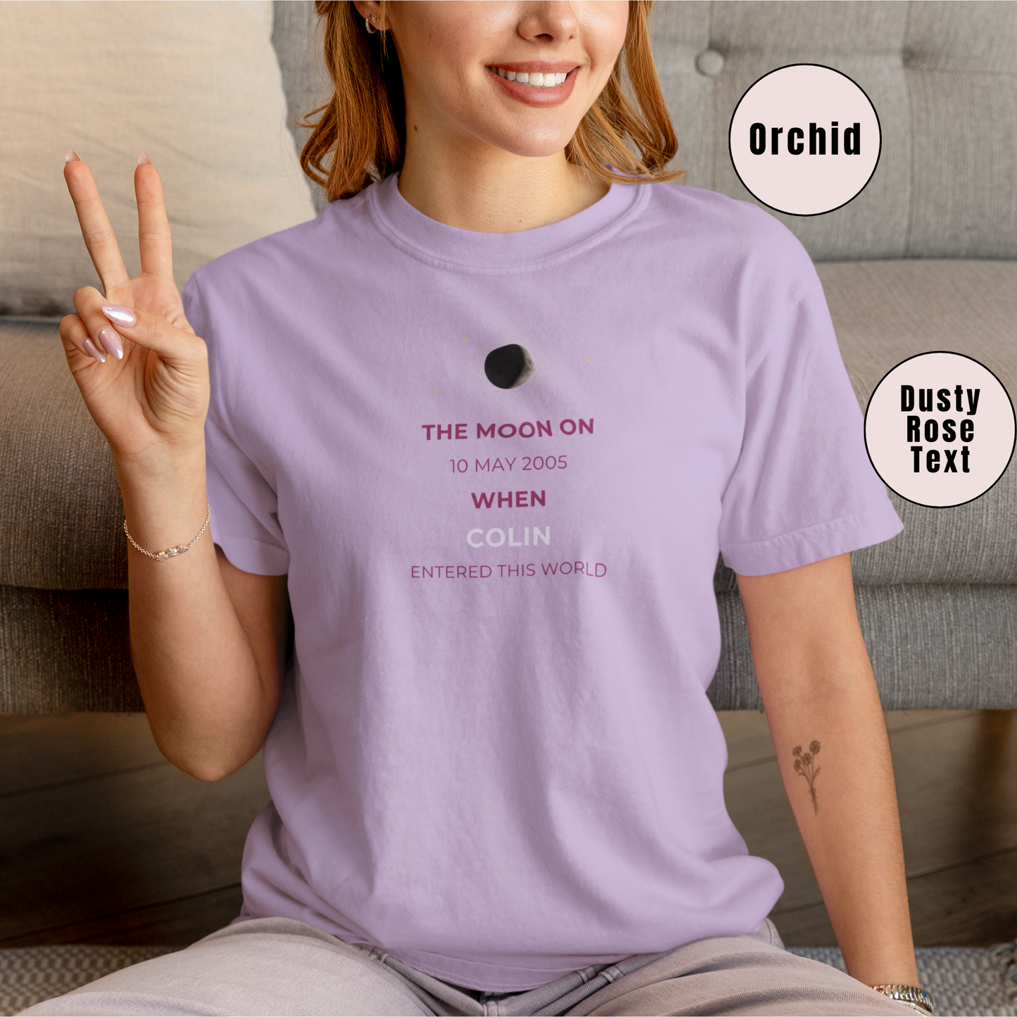 Person wearing a purple t-shirt with text, sitting on a couch.