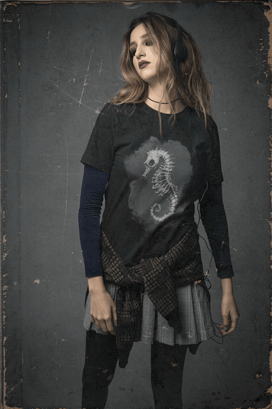 Young woman wearing a black t-shirt with a gothic skeletal seahorse design by Growling Seahorse, styled in alt fashion with layered grunge aesthetic