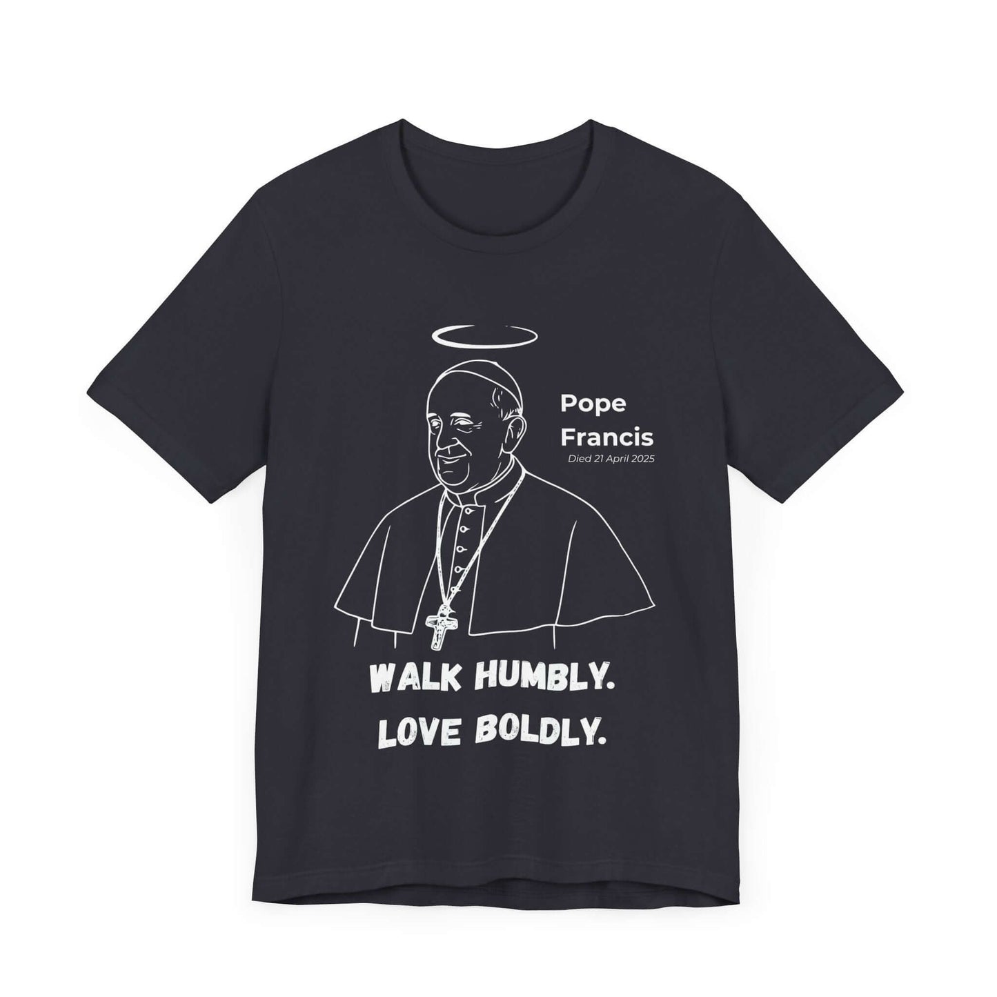Dark grey t-shirt featuring a minimalist white line art portrait of Pope Francis with halo and cross necklace. Below, bold text reads “Walk Humbly. Love Boldly.” A Catholic memorial shirt honoring The People’s Pope.