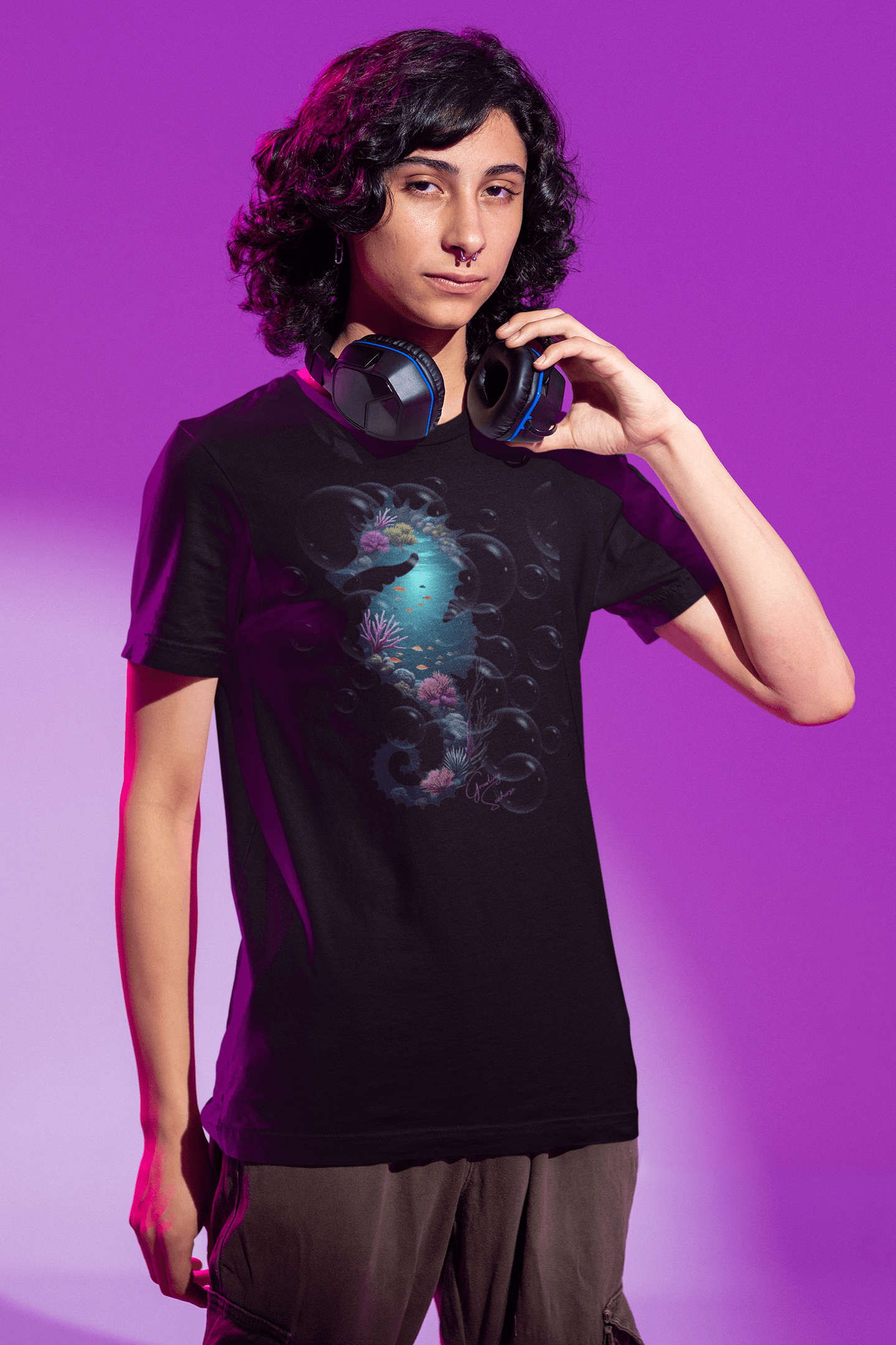 Model wearing a black t-shirt with a glowing underwater seahorse silhouette filled with coral reef details, set against a dreamy purple backdrop—part of the Ocean Dreams collection. Perfect for marine life lovers and deep-sea dreamers.