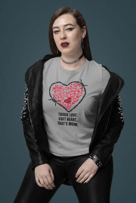 Confident woman in a studded leather jacket wearing a light grey t-shirt with a red barbed wire heart and the phrase “Tough Love. Soft Heart. That’s Mom.” A bold, edgy Mother’s Day tee that fuses funny t-shirt design with punk-inspired quirky fashion.