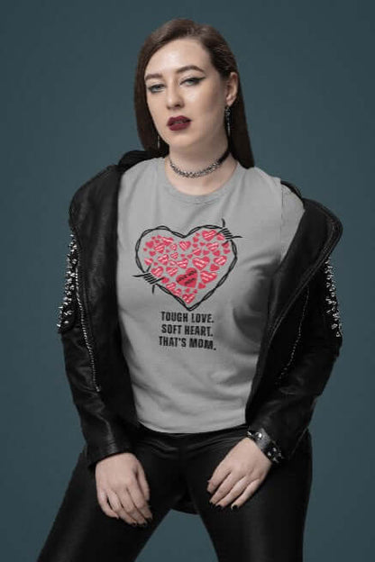 Confident woman in a studded leather jacket wearing a light grey t-shirt with a red barbed wire heart and the phrase “Tough Love. Soft Heart. That’s Mom.” A bold, edgy Mother’s Day tee that fuses funny t-shirt design with punk-inspired quirky fashion.