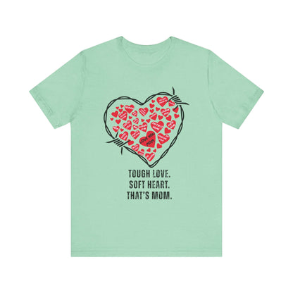 Mint green t-shirt featuring a black barbed wire heart filled with playful red hearts and the quote “Tough Love. Soft Heart. That’s Mom.” A quirky fashion statement for Mother’s Day rebels.