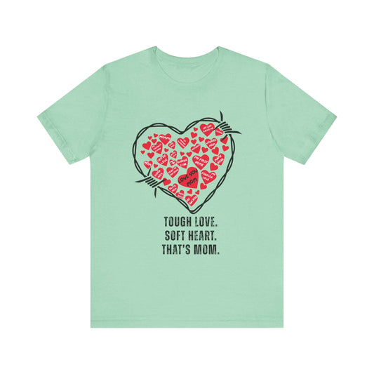 Mint green t-shirt featuring a black barbed wire heart filled with playful red hearts and the quote “Tough Love. Soft Heart. That’s Mom.” A quirky fashion statement for Mother’s Day rebels.
