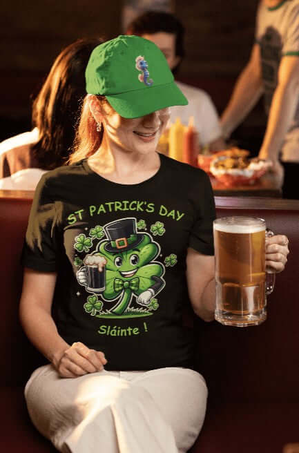 Woman in a pub setting wears a black St. Patrick’s Day T-shirt featuring a vibrant cartoon shamrock in a leprechaun hat and bowtie, raising a pint of beer with the phrase “St. Patrick’s Day – Sláinte!” A festive Irish party tee perfect for parades, pub crawls, and green beer gatherings.
