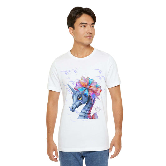Man wearing a white t-shirt with a colorful graphic of a mythical seahorse-unicorn hybrid decorated with a large rainbow satin bow and surrounded by dreamy bubbles. A bold apparel choice combining underwater coral reef vibes with magical, quirky fashion.