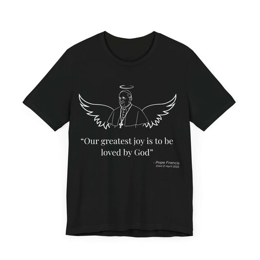 Black shirt with minimalist white illustration of Pope Francis with angel wings and halo. The spiritual quote “Our greatest joy is to be loved by God” is printed beneath. A commemorative Catholic memorial shirt celebrating faith and peace.